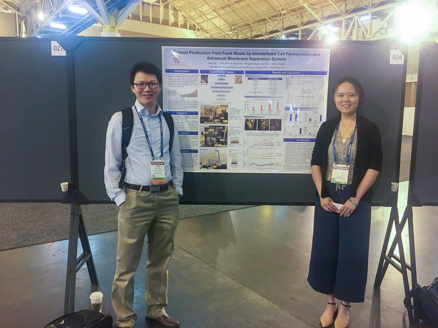 Dr. Haibo Huang and Qing Jin stand in front of their poster at a conference