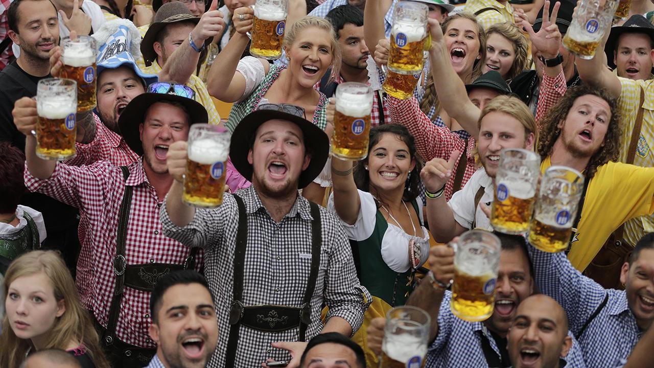 A crowd of people holding up their beers in a "cheers"
