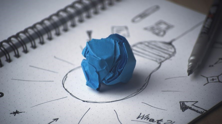 A crinkled ball of blue paper atop a drawing of a light bulb
