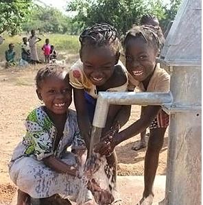 Children happily crowding around a water well