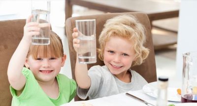Two children holding up glasses of water