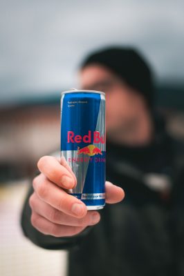a man holds a can of Red Bull energy drink